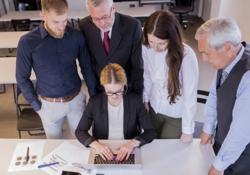 group-businesspeople-looking-woman-using-laptop-workplace